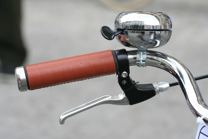 Close-up of a vintage bicycle handlebar with a small bell, soft natural light.