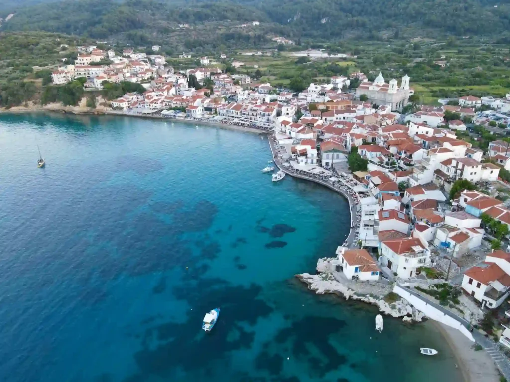 Panoramic view looking down at the red-roofed buildings and blue bay of Kokkari village on Samos island.