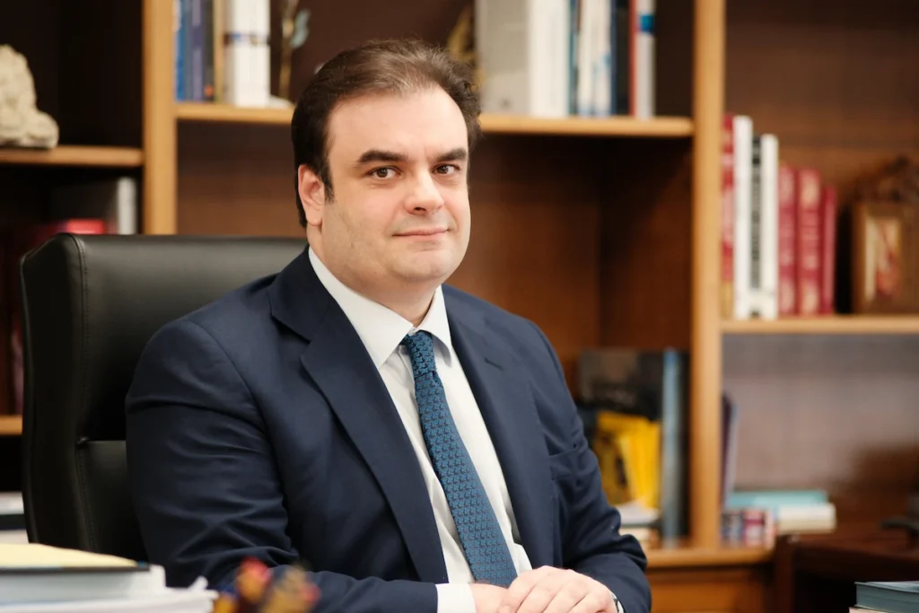 Close-up portrait of Kyriakos Pierrakakis seated inside his office.