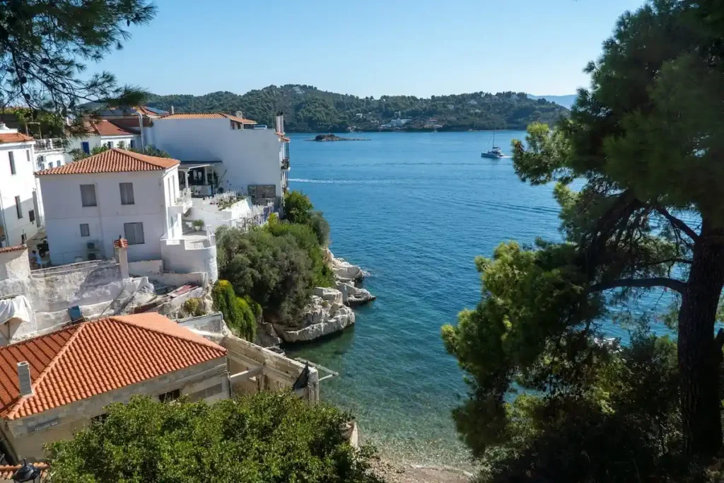 Traditional Greek houses with red ceramic tile roofs standing right near the shoreline in Skiathos.